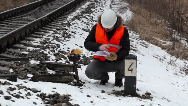 Spoorweg werknemer met documentatie in de buurt van railway — Stockvideo