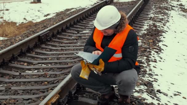 Залізничний працівник перевіряє документацію біля залізниці — стокове відео