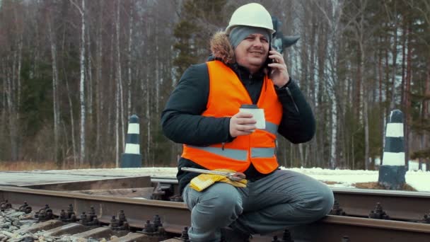 Järnvägen arbetare med kaffe och smartphones på järnvägen — Stockvideo