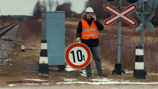 Trabalhador com sinalização rodoviária na travessia ferroviária — Vídeo de Stock
