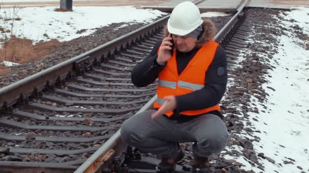 Robotnik pracujący na kolei zły rozmowy na telefon komórkowy w pobliżu kolejowego — Wideo stockowe