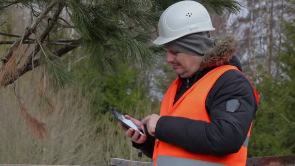 Forest worker with table PC cheking withered branches — Stock Video