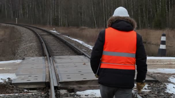 Railroad worker with documentation and adjustable wrench cross railway crossing — Stock Video