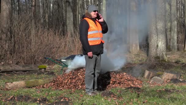 Лісник говорити на смарт-телефону біля багаття — стокове відео