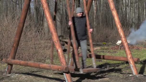 Mann schwingt auf Holzschaukel im Park — Stockvideo