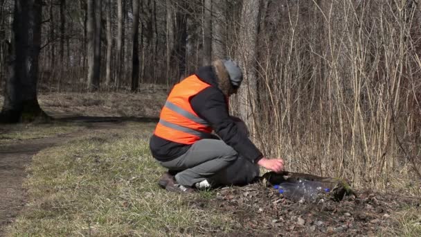 Man pick up empty plastic bottle near path in the park — Stock Video