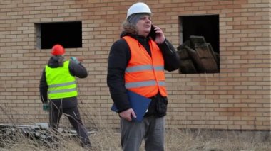 Site Yöneticisi ile akıllı telefon ve işçi building yakınındaki balyoz ile