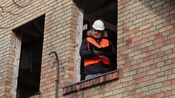 Руководитель участка проверяет документацию в окне второго этажа здания — стоковое видео