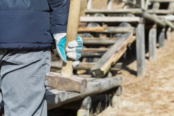 Worker with sledgehammer near to the broken wooden track — Stock Photo, Image