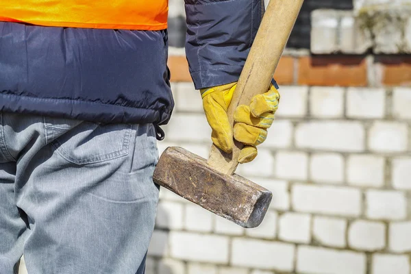 Pracownik z młotem w pobliżu mur z cegły — Zdjęcie stockowe