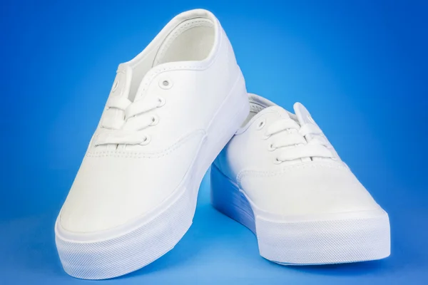 Plimsolls de forma plana blanca sobre fondo azul —  Fotos de Stock