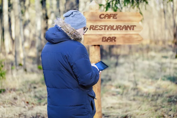 Man met tablet Pc in de buurt van bord met het opschrift café, bar, restaurant — Stockfoto