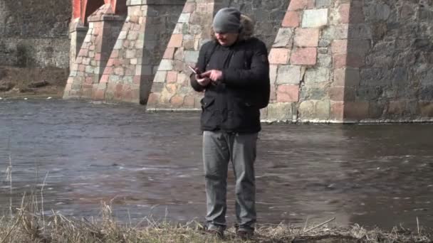 Człowiek za pomocą tabletu Pc w pobliżu rzeki — Wideo stockowe