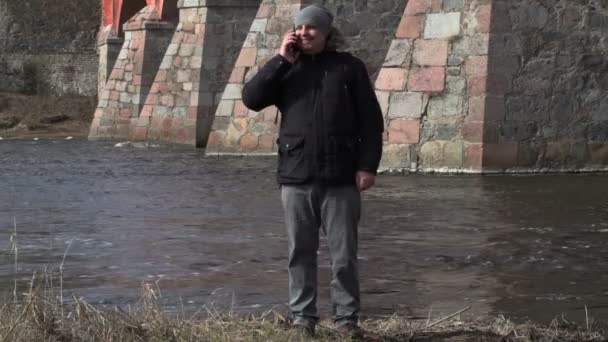 Ο άνθρωπος μιλάει στο έξυπνο τηλέφωνο κοντά στο ποτάμι — Αρχείο Βίντεο