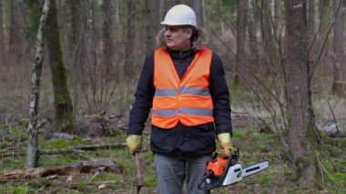 Oduncu chainsaw ve ormanda balta ile 