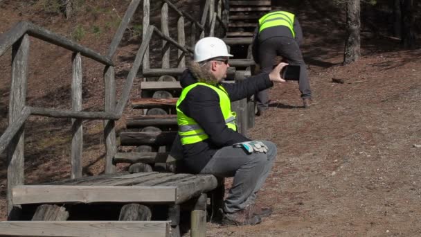 Werknemers met tablet Pc en voorhamer in de buurt van de gebroken houten bijhouden — Stockvideo