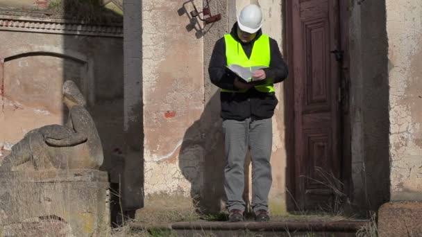 Inspetor de construção verificando documentação perto da porta do edifício — Vídeo de Stock