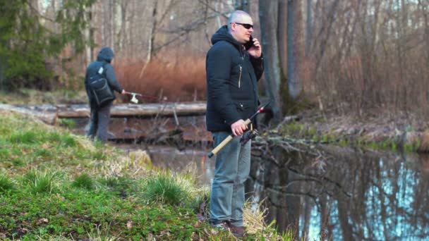 Fishermans con cañas de pescar y teléfono inteligente en la orilla del río — Vídeos de Stock