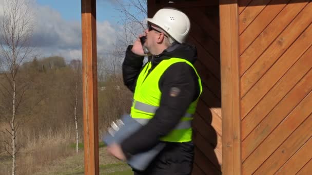 Stavební inženýr, mluvit na smartphonu na dřevěné konstrukce budovy — Stock video