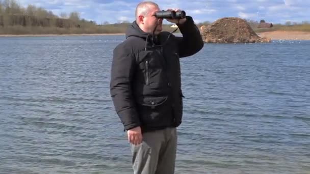 Mann beobachtet Vögel am See — Stockvideo