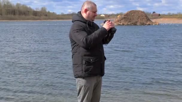 Man met verrekijker aan het meer — Stockvideo