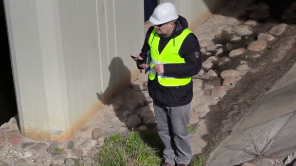 Ingeniero de comprobación y uso de PC de mesa cerca de la construcción del puente — Vídeo de stock