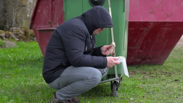 Sem-abrigo com alimentos perto de contentor de resíduos — Vídeo de Stock