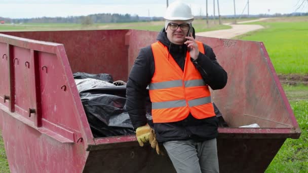 Robotnik rozmowa na inteligentnego telefonu w pobliżu pojemnika na odpady — Wideo stockowe