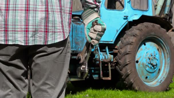 Worker with adjustable wrench near the tractor — Stock Video