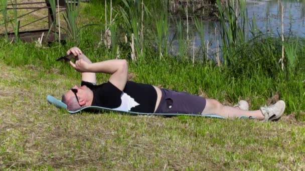 Man using tablet PC near lake in summer — Stock Video