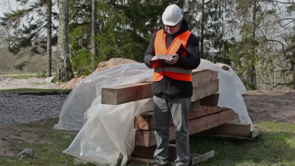 Будівельний інспектор пише біля будівельних матеріалів — стокове відео