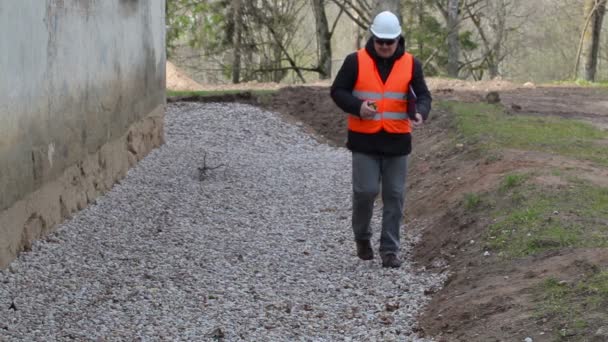 Stavební inspektor na cestě s páskou opatření nedaleko svahu — Stock video