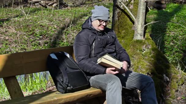 Man med två böcker i parken på bänk — Stockvideo