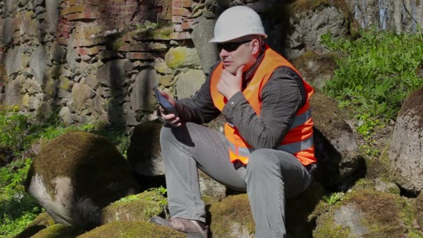 Строительный инспектор думает около древней стены — стоковое видео