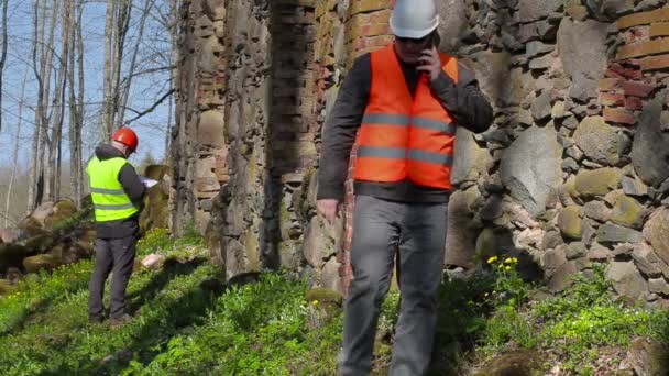 Ispettore di costruzione che parla su smart phone vicino al muro antico prima del restauro — Video Stock