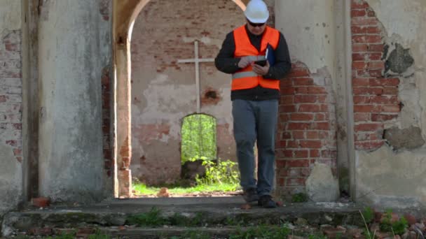 Строительный инспектор с помощью планшетного ПК в старой церкви перед реставрацией — стоковое видео