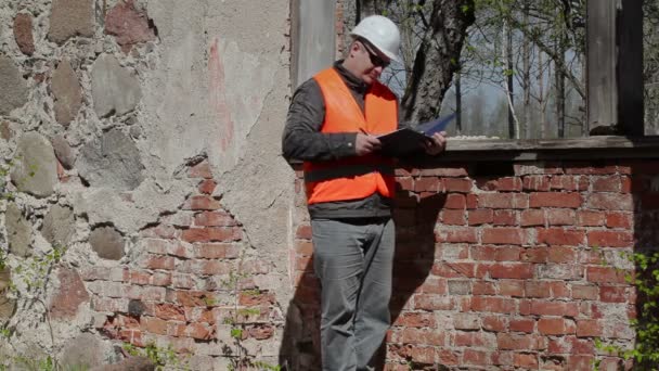 Bauinspektor schreibt nahe Fenster — Stockvideo