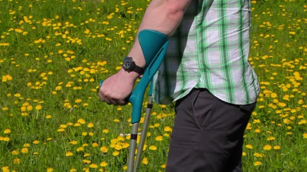 Niepełnosprawny mężczyzna z kulami na polu mniszek — Wideo stockowe