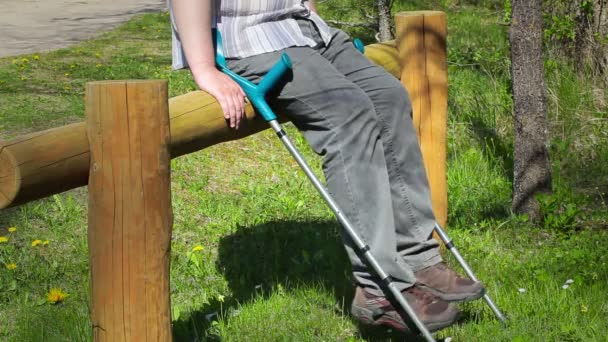 Hombre discapacitado con muletas sentado y moviendo sus piernas — Vídeo de stock