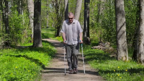 Disabled man with crutches walking in park — Stock Video