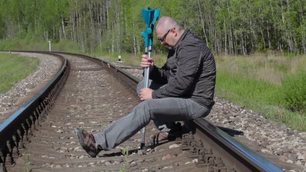 Depressed disabled man with crutches sitting on railway — Stock Video