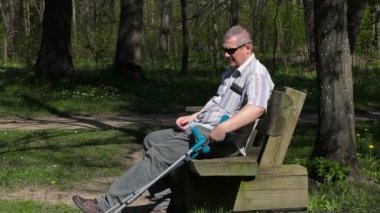 Koltuk değneği ile Engelli adam zevk doğa parkta bankta