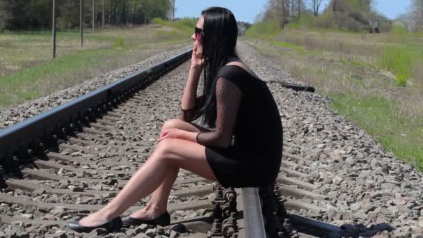 Mujer sentada en el ferrocarril y hablando por teléfono inteligente — Vídeo de stock