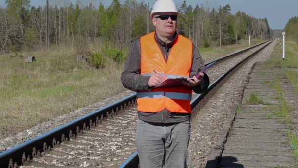 Trabajador ferroviario escribiendo cerca del ferrocarril — Vídeos de Stock