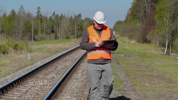 Trabajador ferroviario caminando y escribiendo cerca del ferrocarril — Vídeo de stock