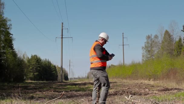 Eletricista tirar fotos no telefone inteligente e inspecionar as linhas de alta tensão condição técnica — Vídeo de Stock