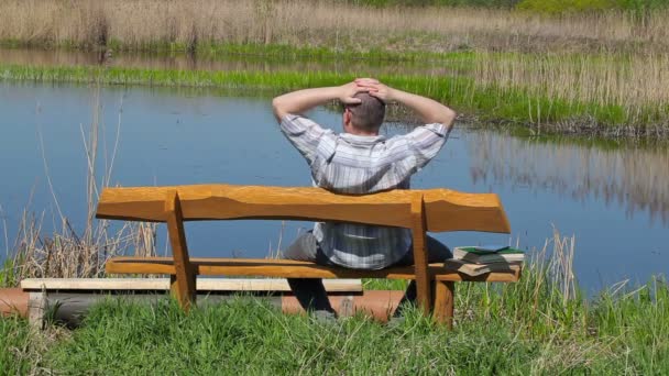 Man relaxing on the bench near river — Stock Video