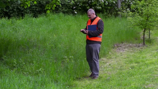 Gestionnaire d'aménagement paysager prendre des photos sur le téléphone intelligent près de l'herbe de coupe de mauvaise qualité — Video