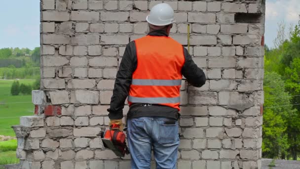 Bauarbeiter messen an der Ziegelwand — Stockvideo