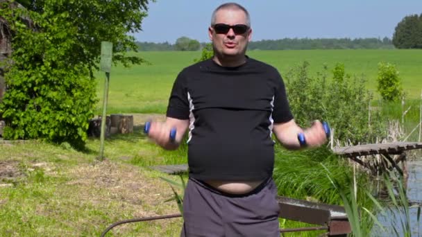 Mann mit Übergewicht macht Übungen mit Kurzhanteln für Bizeps — Stockvideo